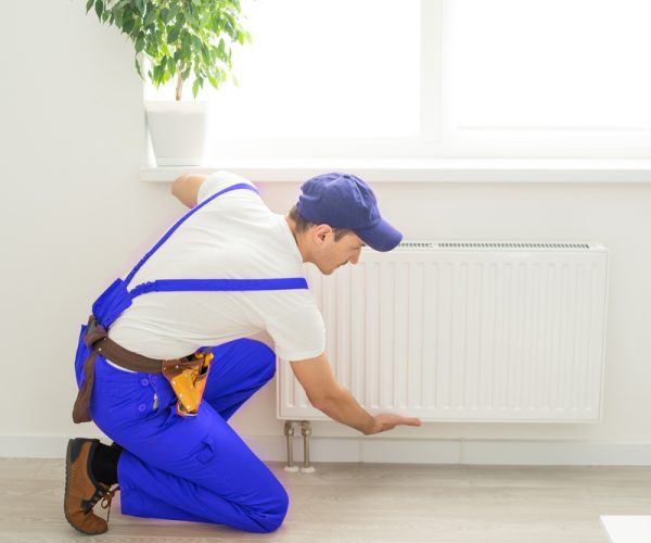 Plumber,Man,Is,Blocking,Repairs,Radiators,Of,Heating,Battery,In